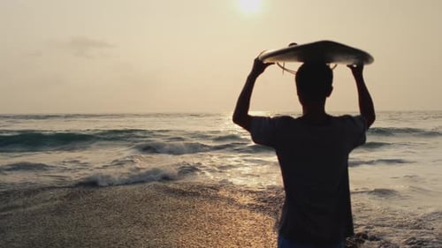 Un surfeur tient une planche de surf pour une session de surf Surf, un homme marchant sur la plage, Bali, Indonésie