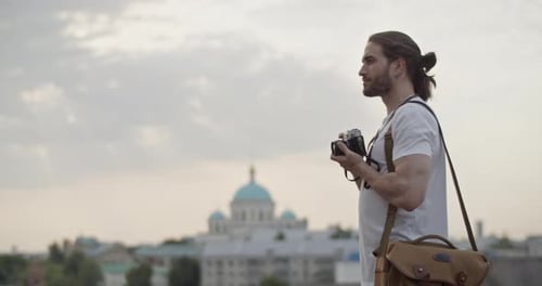 Man Taking Pictures with Vintage Camera in City