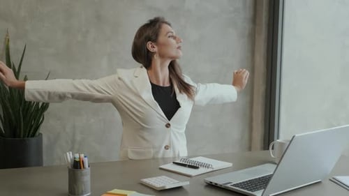 Tired Woman Stretching at Desk in Office