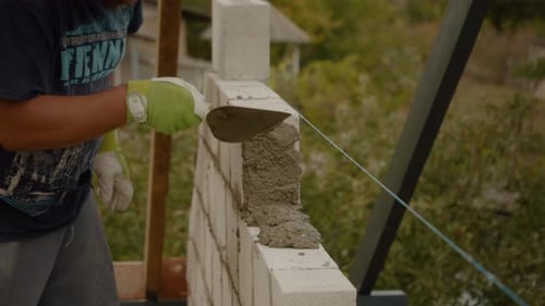 Worker builds concrete wall while constructing a new house in a residential area
