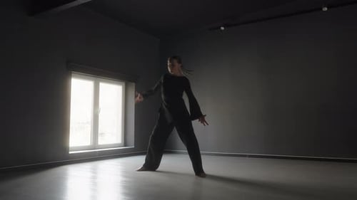 Woman in Black Interpretive Dancing in Dark Studio with Bright Window