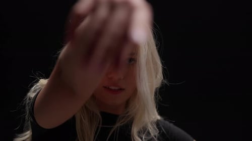 Young Woman in Policemans Hat Dances in Studio Against Black Background