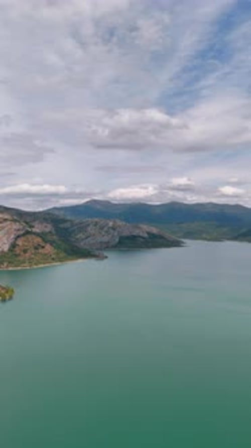 Peaceful smooth surface of the turquoise lake surrounded by the mountain range.
