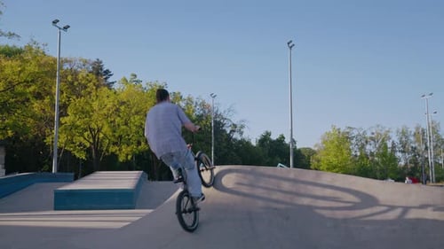 Young Adult Biking and Performing Stunts in Skatepark