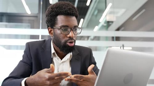 Confident african american businessman in formal suit talking on video call using a laptop