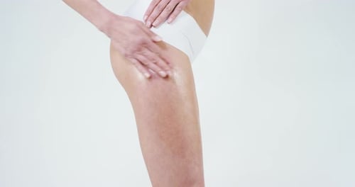 Woman Applies Oil to Leg in a Studio