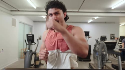 Homem correndo na esteira e praticando boxe nas sombras enquanto sorri na academia