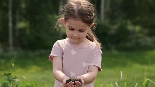 Girl Holding Small Plant in Meadow