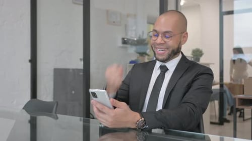 Young Adult Celebrates News on Phone in Office