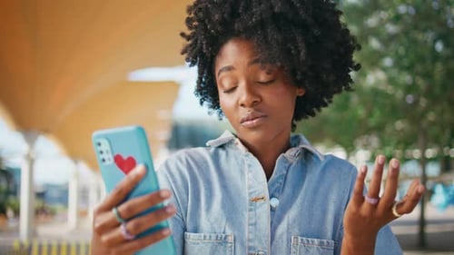 Vídeo de mulher encaracolada por telefone celular sentada na rua em closeup Adolescente africana