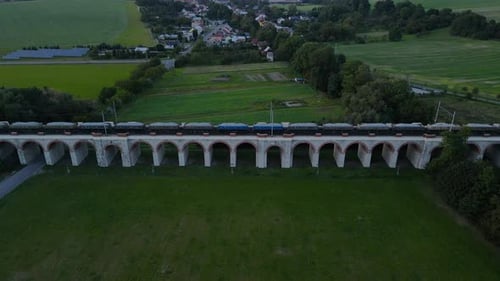 Aerial view of a train viaduct with a passing train and the surrounding countryside in the