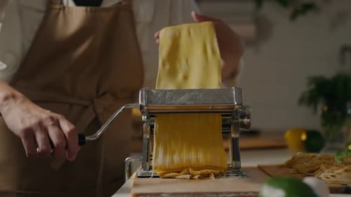 Italian, professional chef prepares with concentration. Takes hand while supporting fresh spaghetti