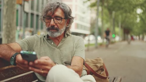 Man Using Mobile Phone on City Bench