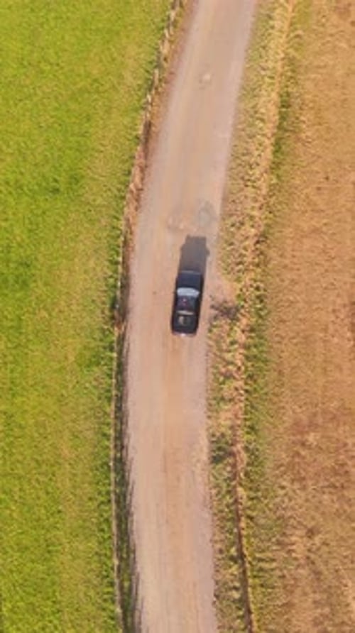 Aerial view of black convertible sports car driving on countryside road, France.