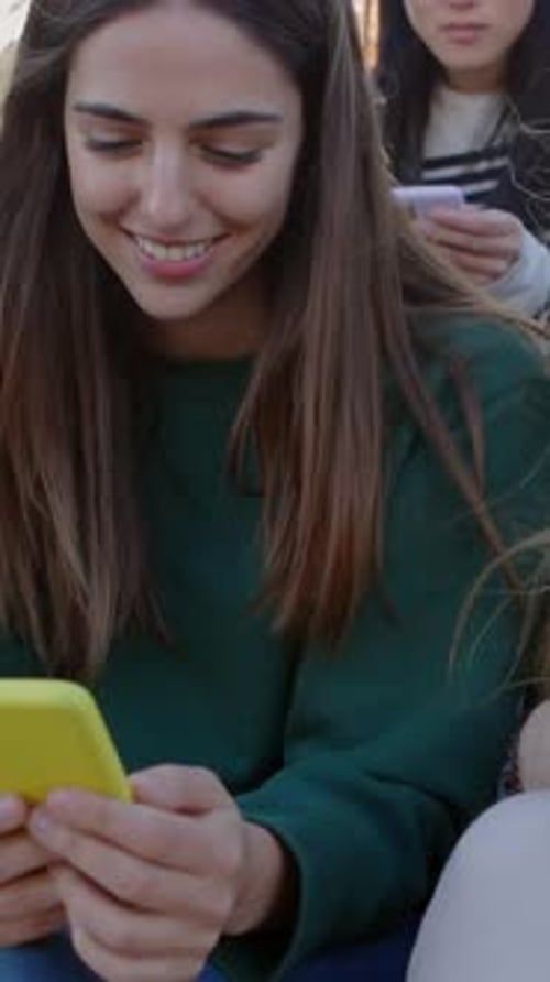 Young Women Using Smartphones Together Outside