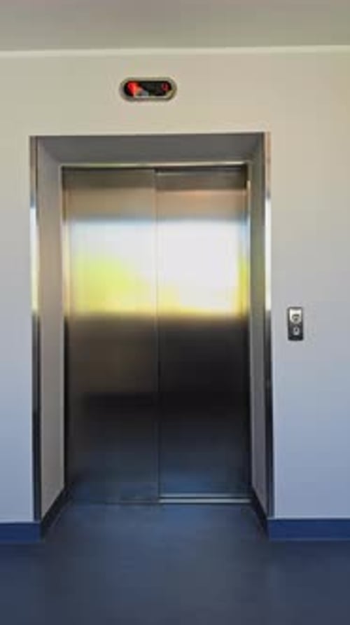 Esta es una entrada de ascensor moderna que cuenta con puertas plateadas brillantes colocadas en un lugar luminoso y acogedor