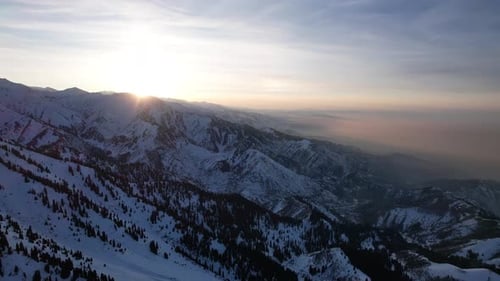 Epischer rot-orangefarbener Sonnenuntergang in den verschneiten Bergen