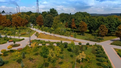 Gepflegter grüner Park mit grünen Bäumen an sonnigen, klaren Tagen.
