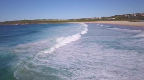 Aerial view of ocean waves crashing the sandy beach