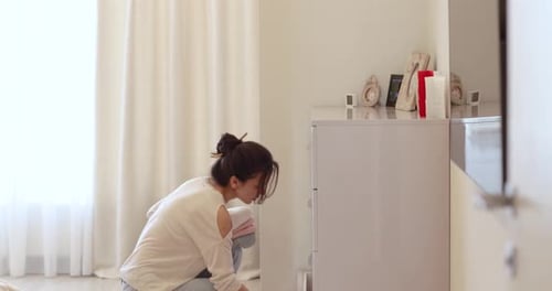 Caucasian Woman Opens a Drawer with Folded Towels in the Room