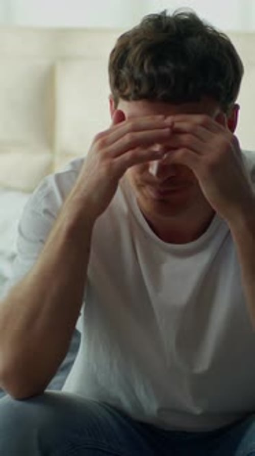 Sad Man Sitting on Bed With Head in Hands