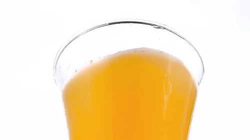 Pouring Orange Beverage Into a Clear Glass