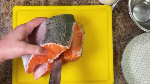 Cutting salmon fish with a knife for further cooking, preparing the fillet and removing the bones.