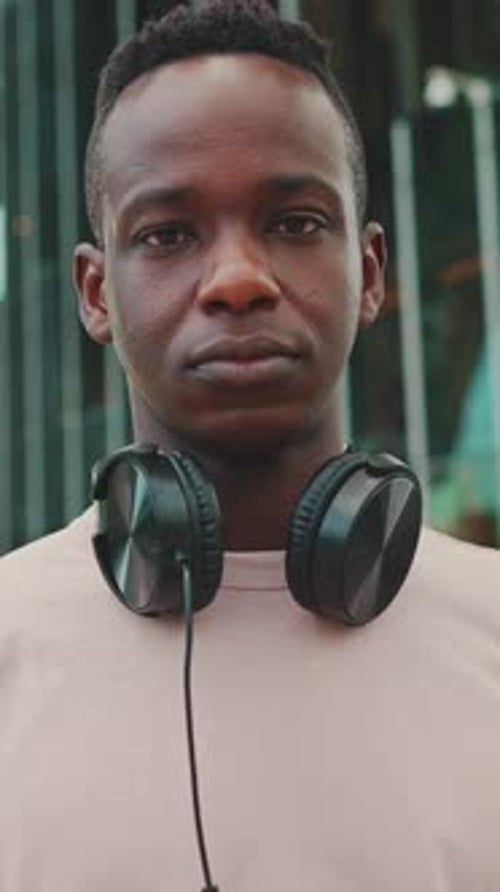 Close-up of young student standing outside of university in headphones
