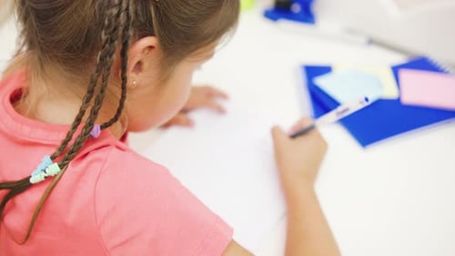 Girl Draws at Table with Colorful Notes