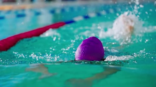 Woman Swimmer with Purple Cap Swimming in Pool