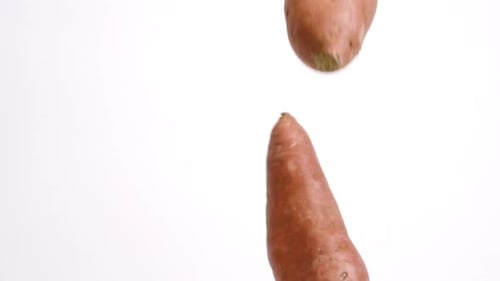 Sweet Potatoes Falling in Slow Motion Against White Background