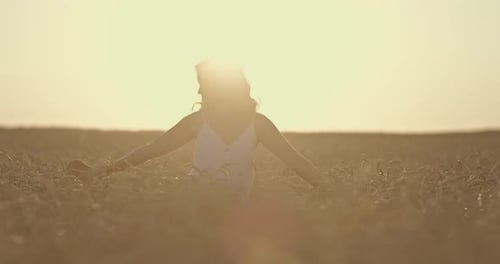 Beautiful Girl is Spinning in the Rays of the Sun a Golden Wheat Field