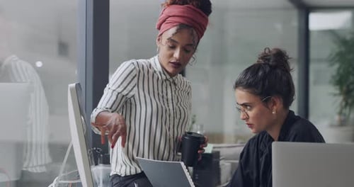 4k video footage of two young businesswomen using a computer together in a modern office