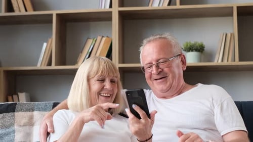 Cheerful Senior Couple Using Smartphone at Home