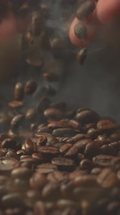 Super Slow Motion Shot of Falling Roasted Coffee Beans From Hand with Smoke in Macro Vertical Close