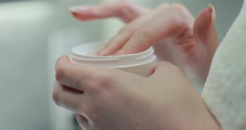 Woman Applies Moisturizing Cream from Jar