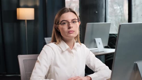 Smiling Woman Sits at Desk in Modern Office