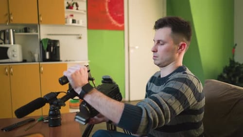 Man Adjusting Tripodmounted Camera with Microphone in Home Studio