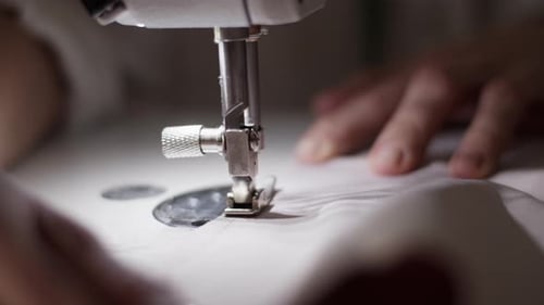 Femme anonyme cousant un tissu sur une machine à coudre