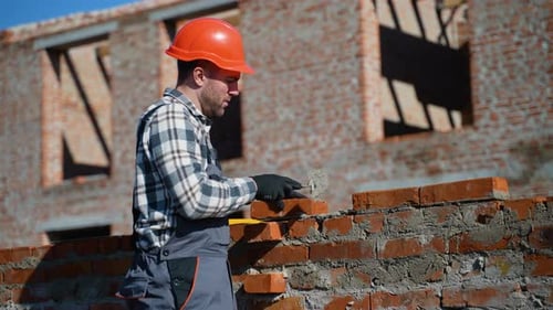 Builder Carefully Laying Bricks at Construction Site