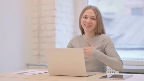 Woman Gives Thumbs Up While Working on Laptop