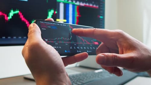 Hands with a Mobile Phone Checking Stock Market Data