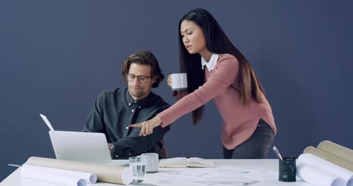 4k video footage of two young architects using a laptop while working together in a modern office