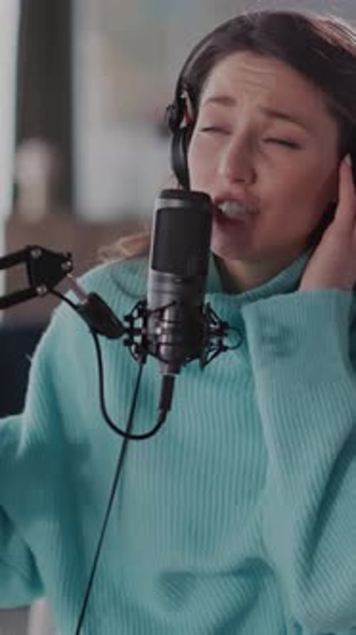 Woman Singing Into Microphone With Headphones On