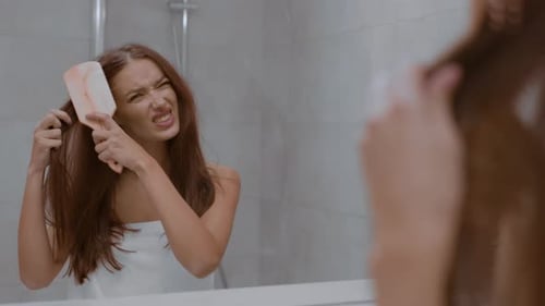 Woman Struggles to Brush Tangled Hair in Bathroom