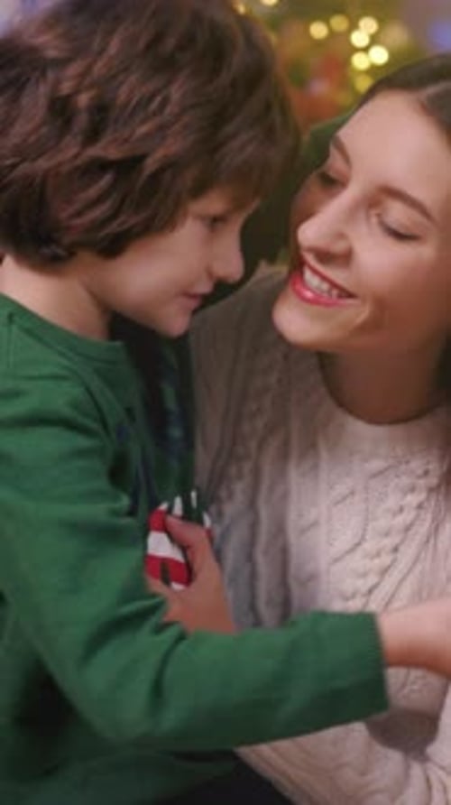 Boy Giving Gift To Woman Hugging At Christmas