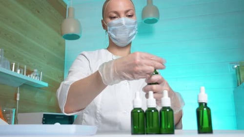 Woman Assembling Green Dropper Bottles in Bright Lab