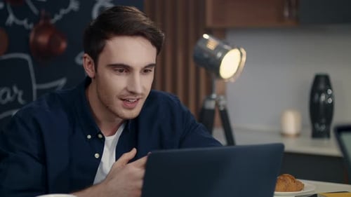 Man Engaged in Video Call on Laptop at Home