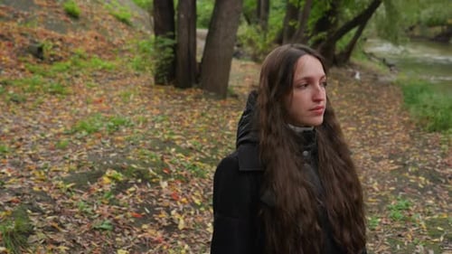 Woman By River Reflective Woman Strolling Near Water During Autumn Season Serene Lady with Long Dark