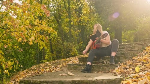 Joven músico ensaya la canción Autumnal woodland park golden light